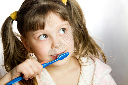 有刷牙的女孩童年眼睛牙齿头发蓝色洗手间孩子脸颊刷子背景图片