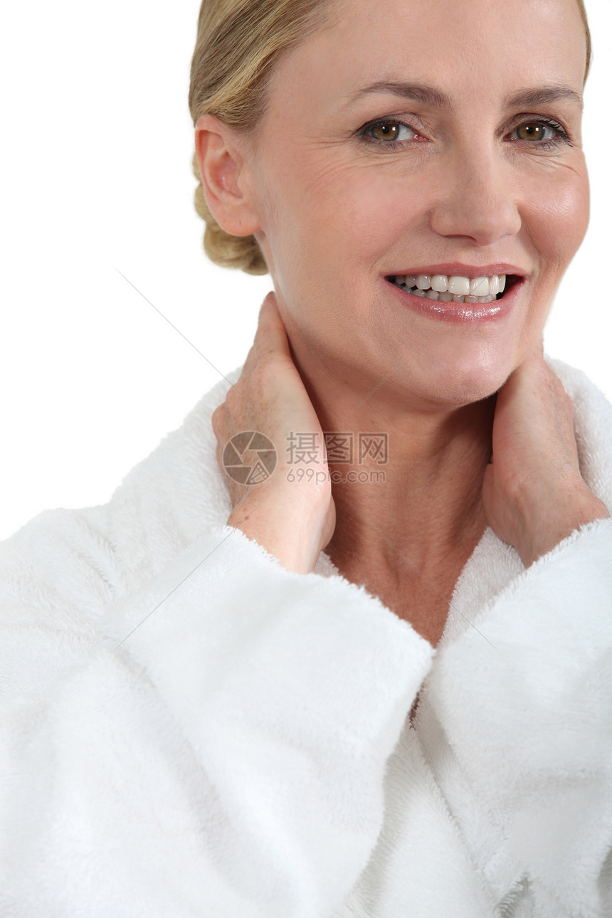 穿着浴袍的妇女用双手在脖子后微笑图片