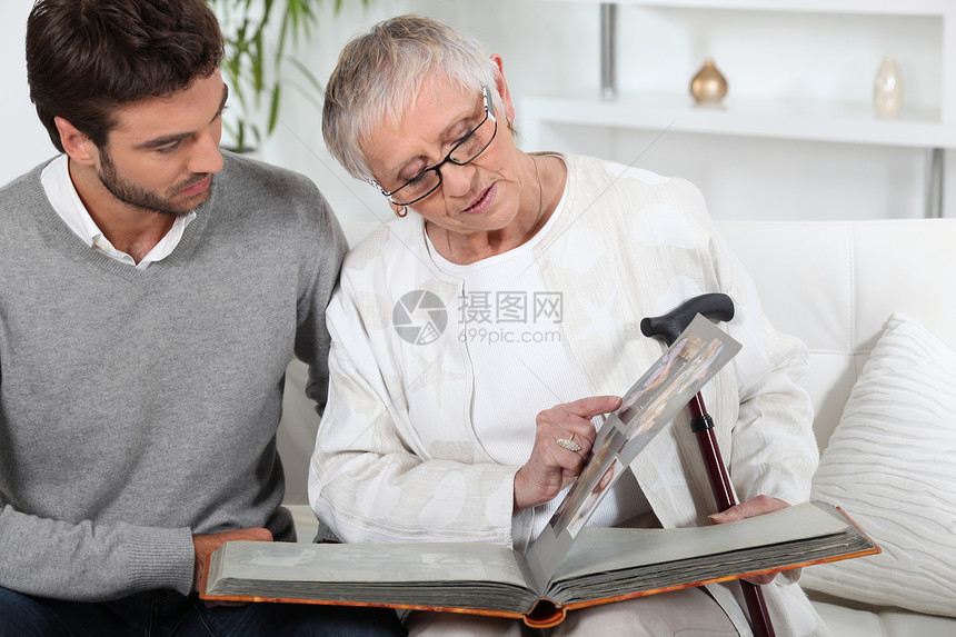 与儿子一起看相片的老年人男人教育男性白色棕色女士关爱母亲眼镜灰色图片