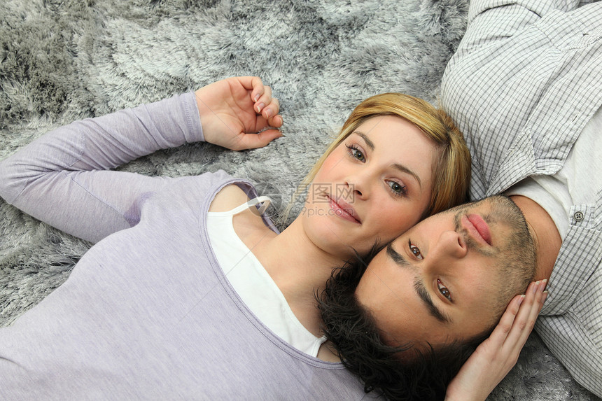 躺在灰色地毯上从上到下倒在尾巴上的年轻夫妇图片