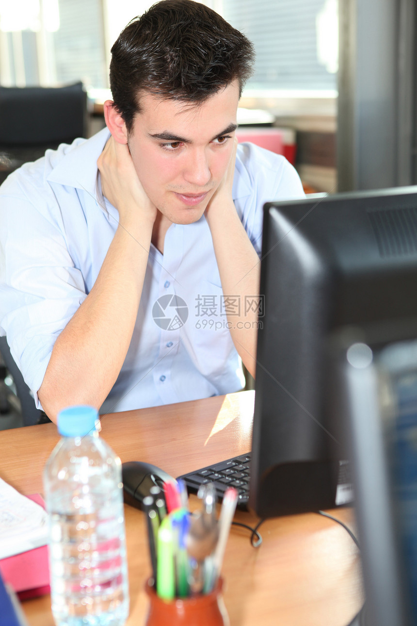 青年男子在台式电脑前把他的脖子扣在桌面电脑前图片