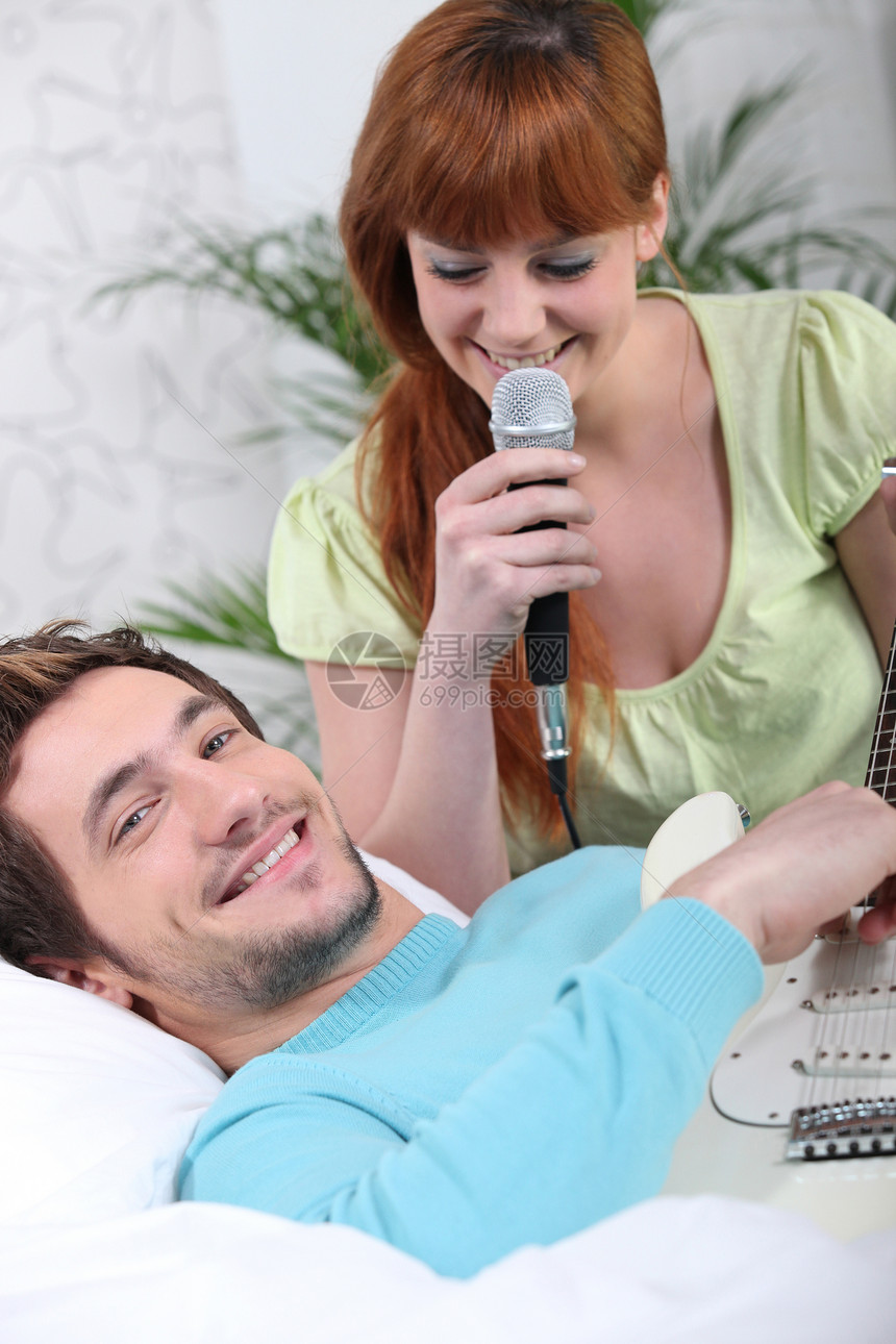 一个男人弹吉他 和一个女人在家里唱歌图片