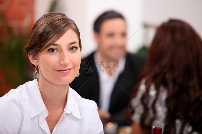 关注的焦点是坐在一家餐馆里与背景中其他餐厅共餐的妇女图片