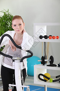 远动服体操中的年轻女子自行车疾病椭圆机女士中心运动活力力量灵活性跑步机背景