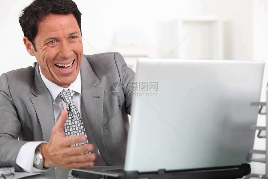 男人在电脑上歇斯底里地嘲笑他的笔记本电脑图片