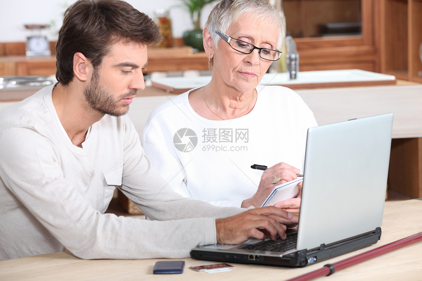 一位年轻男子和年长妇女肖像屏幕女士老年教学孙子笔记电脑服务学习桌子图片