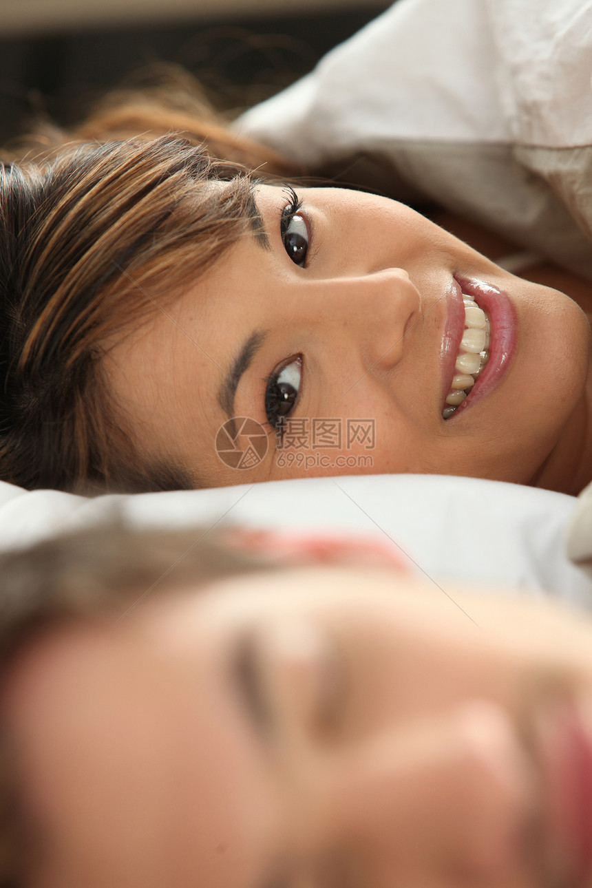 与伴侣在床上微笑的女人图片