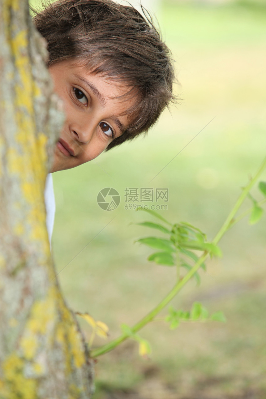 年轻男孩在树旁偷笑图片