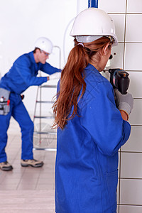 女性电工钻墙壁改造工作建筑力量插座钻孔安装房子女士团队工人高清图片素材