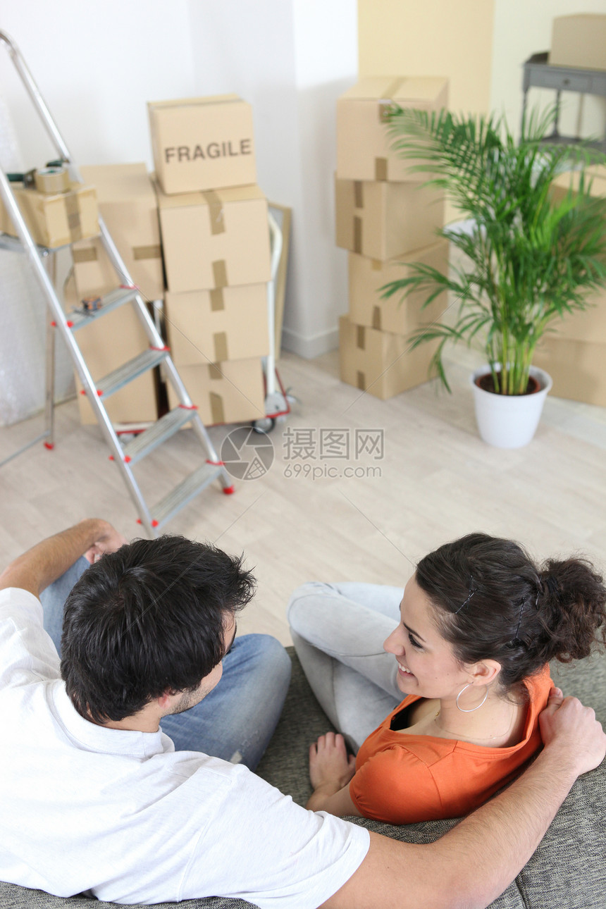 坐在沙发上的年轻夫妇财产长椅微笑盒子女性男性纸板夫妻公寓梯子图片