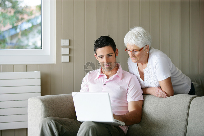 年轻男子和一位年长妇女看笔记本电脑图片