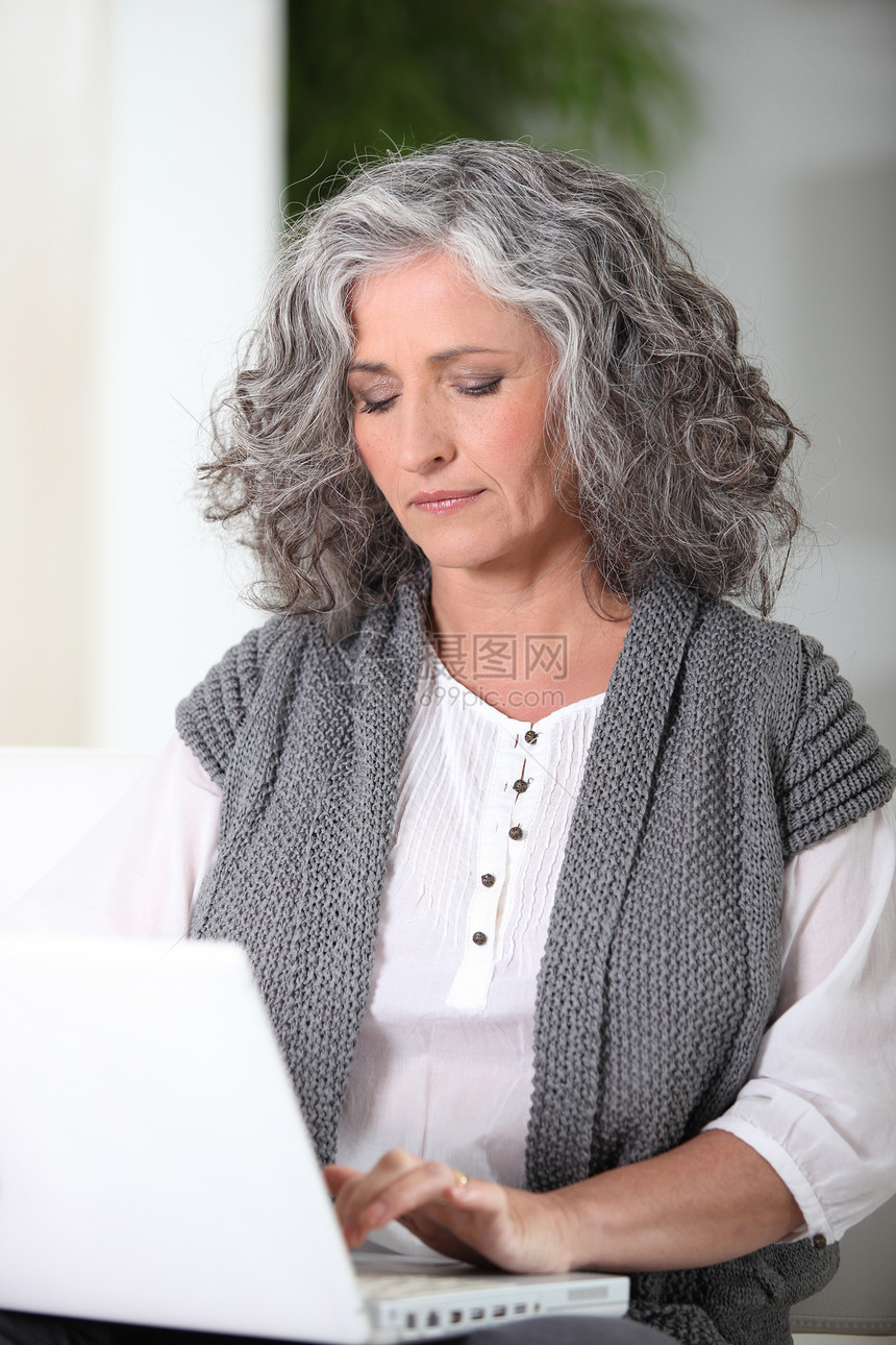 利用手提笔记本电脑工作的妇女拖把电子邮件卷发职业自由职业者女士波浪状胡椒白色头发图片