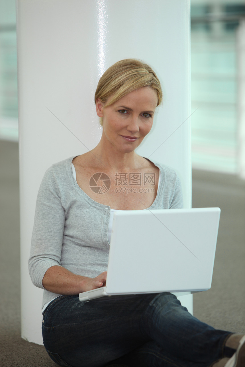 妇女用膝上型计算机坐在专栏旁边图片