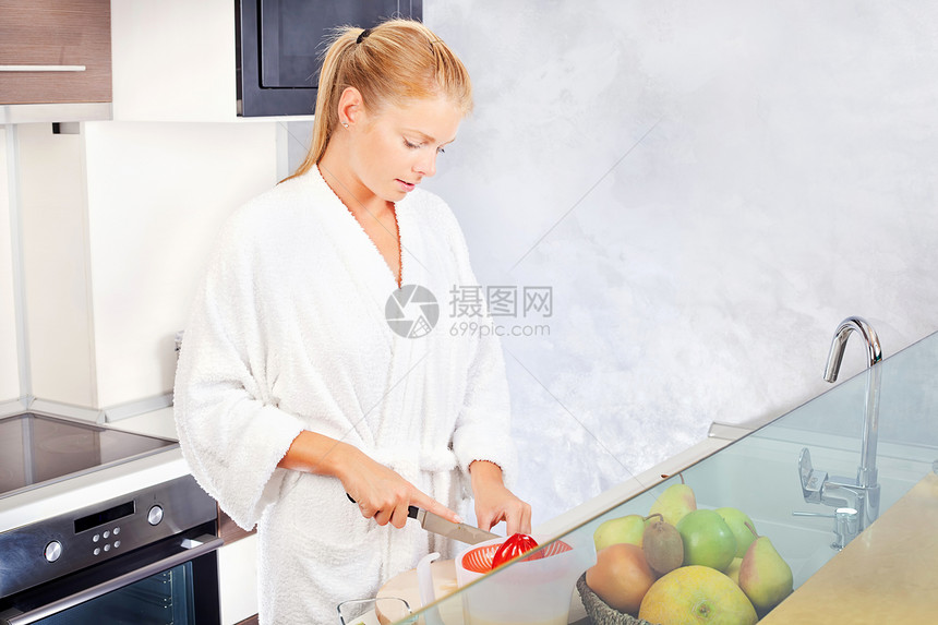 女人在厨房做早间果汁金发水果奇异果早餐食物女性橙子微笑长袍图片
