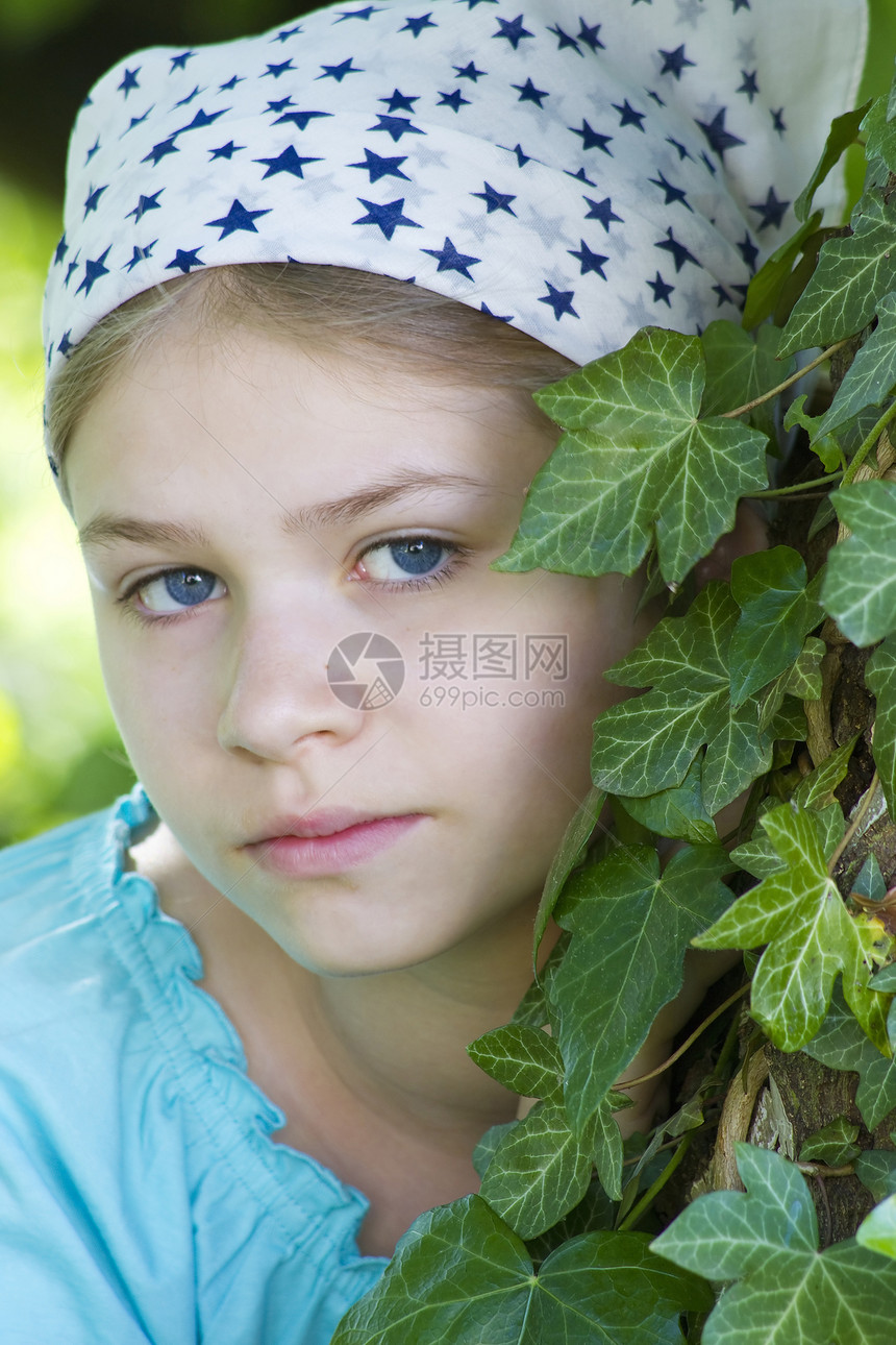 在夏季绿色公园的树旁站立着年轻女孩的肖像图片