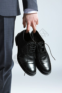 商务人士手握着鞋子 关上门男装黑色礼服购物背景图片