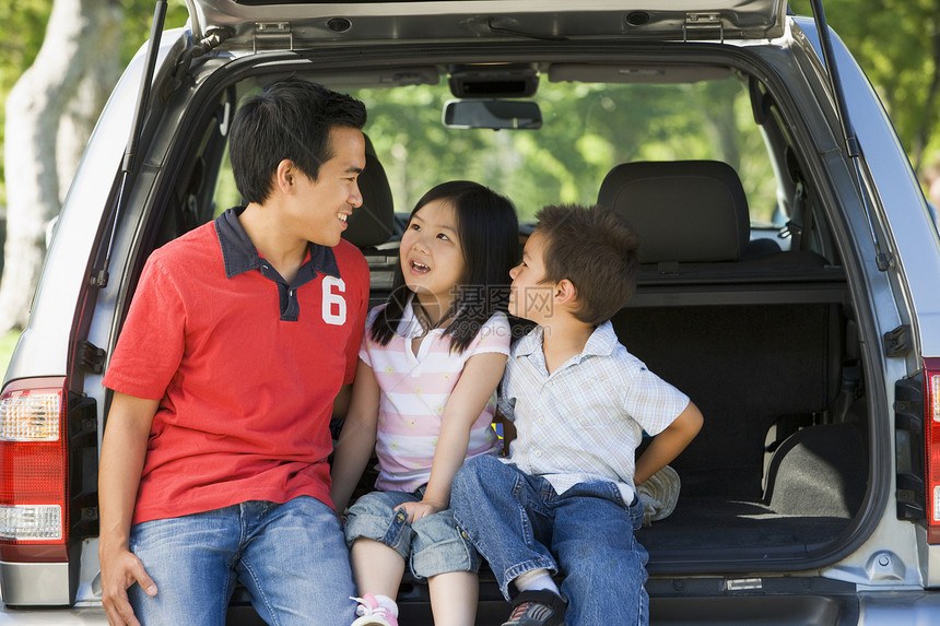 男人和两个孩子坐在面包车后面微笑着成人爸爸家庭活动三个人父母兄弟女性商务车树干图片