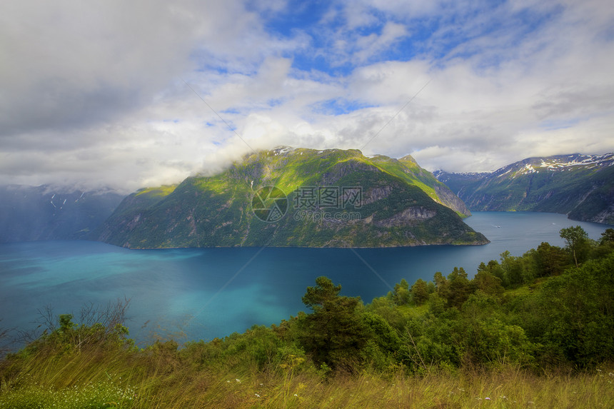 Geiranger 视图石头悬崖海岸天空山坡植物群国家峡湾蓝色反射图片