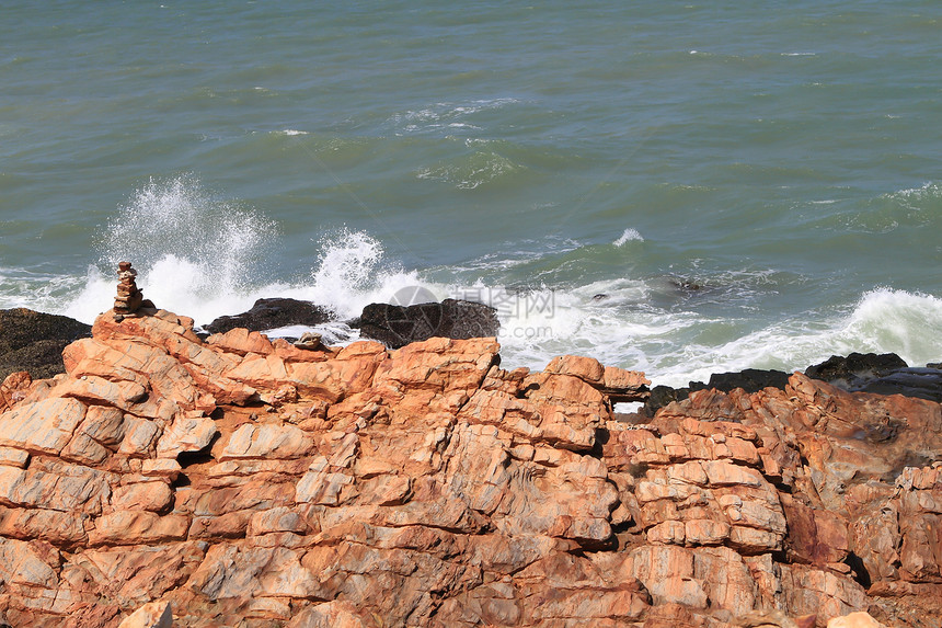 热带海滩上的石头蓝色海岸线冲浪岩石海浪阳光天空异国场景海洋图片