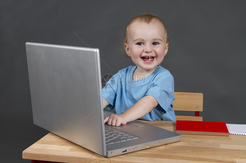 带有灰色底笔记本电脑的婴儿婴儿技术童年桌子孩子机构快乐儿童电子产品办公室背景图片