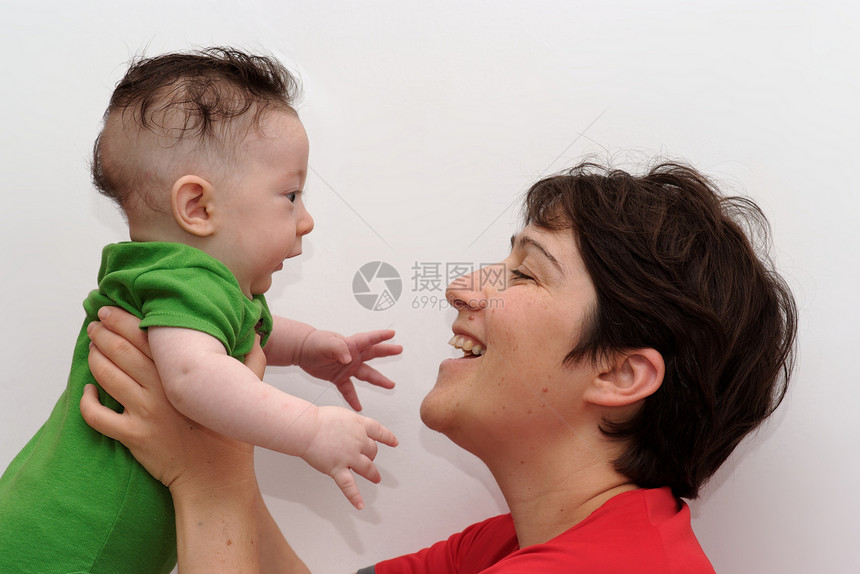 可爱的婴儿被他笑着的母亲剖面观所抱住图片