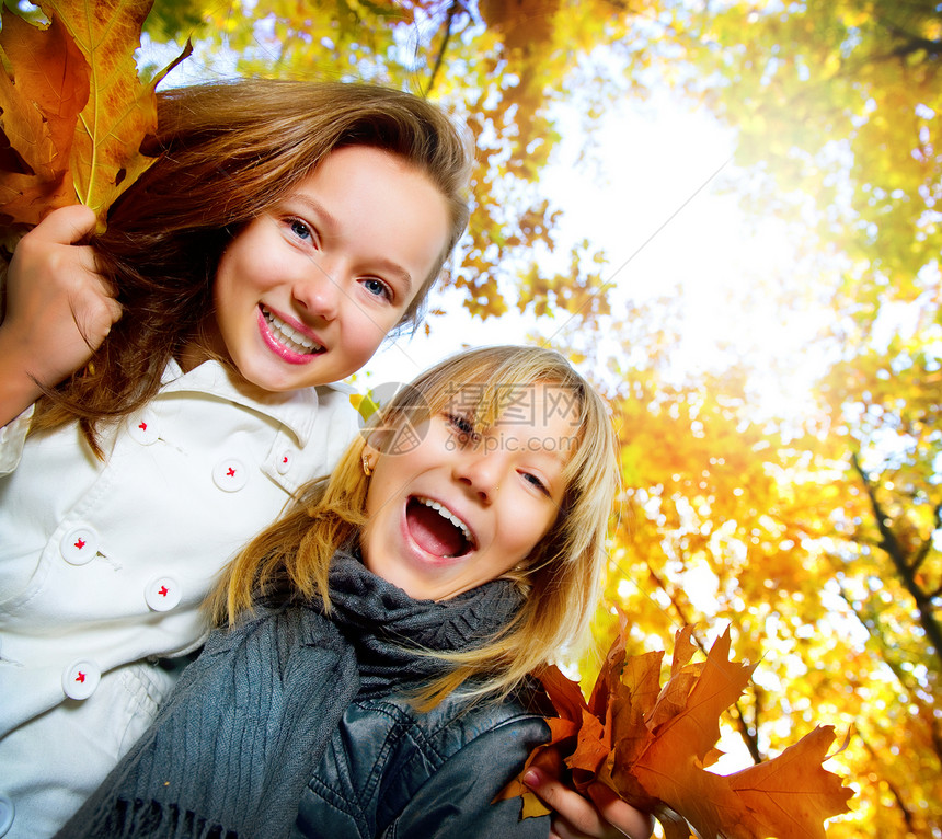 美丽的年轻女孩在秋天公园玩得开心学校女学生家庭姐姐女朋友乐趣青少年微笑天空牙齿图片