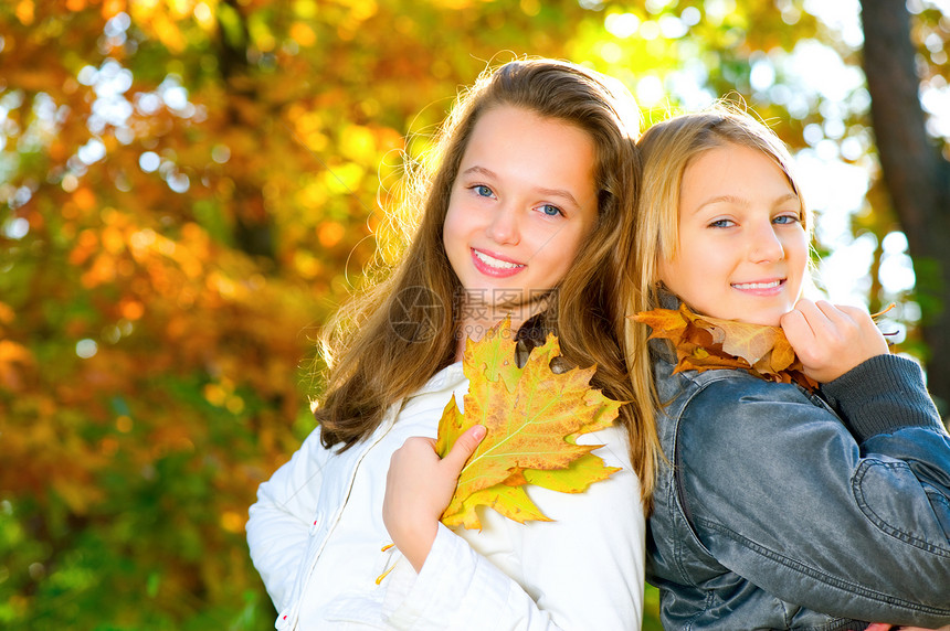 美丽的年轻女孩在秋天公园玩得开心树叶学生学校青年青少年女朋友微笑牙齿乐趣姐姐图片