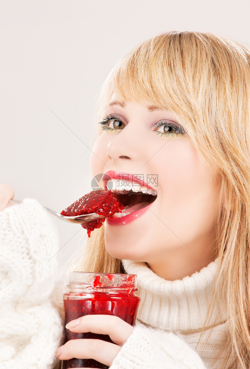 带着草莓果酱的快乐少女少女羊毛毛衣食物勺子女性饮食女孩微笑覆盆子享受图片