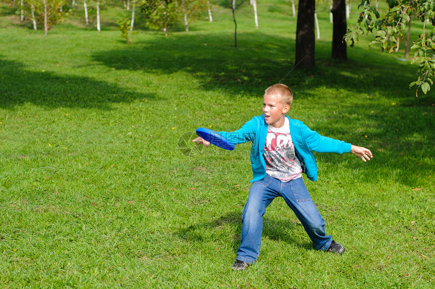 小男孩玩飞盘青年活力行动公园速度闲暇手臂牛仔裤游戏男生图片
