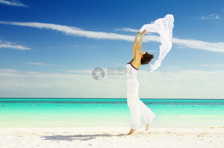 带着白沙龙的快乐女人跳跃自由享受海滩假期海岸女孩天空蓝色热带图片
