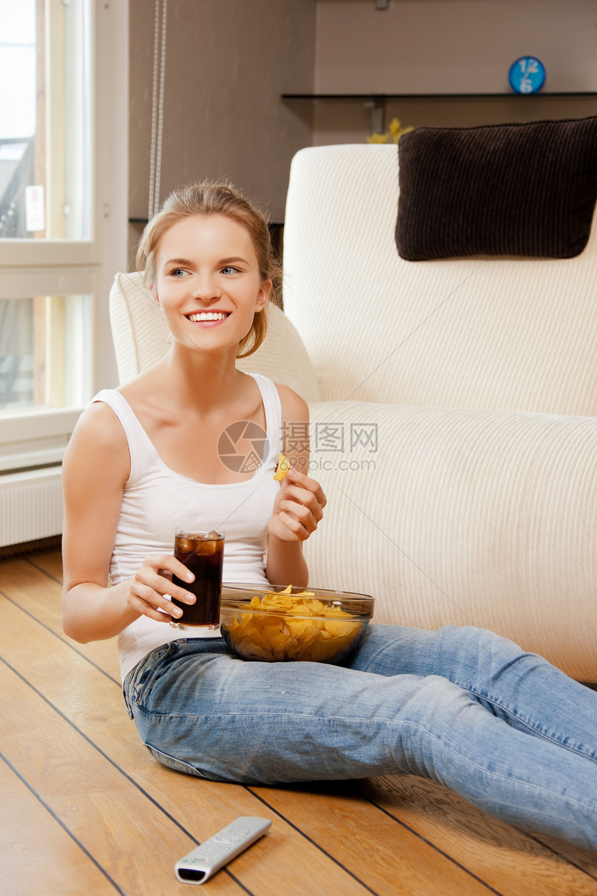 带遥控器的笑着微笑的少女娱乐女性食物控制玻璃可乐青年视频电视筹码图片