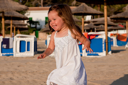 可爱的小女孩笑着在夏天海滩上玩阳光女性快乐女孩乐趣蓝色假期海岸喜悦孩子们蓝色的高清图片素材