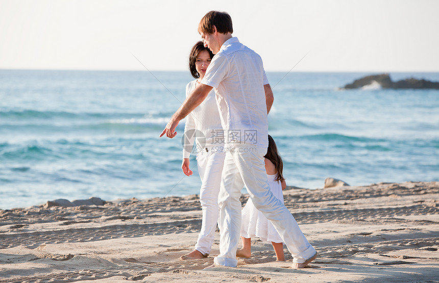 快乐的年轻家庭 和女儿在沙滩上假期孩子成人旅游女孩海滩父母团体蓝色女士图片
