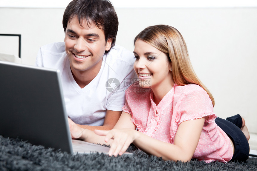 使用笔记本电脑的年轻夫妇互联网成人女士技术女朋友地毯房子女性男朋友闲暇图片