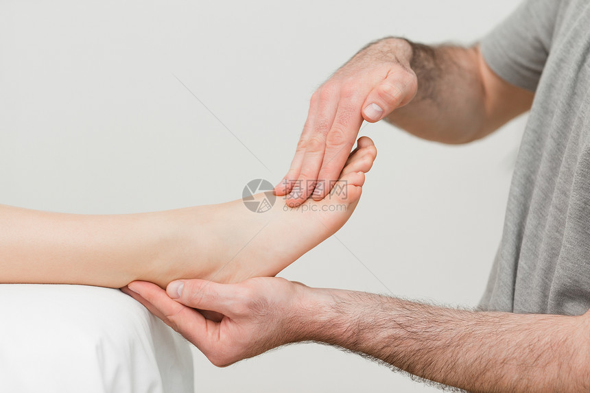 医生握着病人的脚双手拉伸韧带药品肌肉按摩医疗脊椎肌腱说谎图片