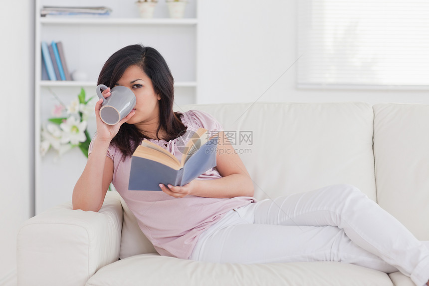 女人躺在沙发上喝杯子酒图片