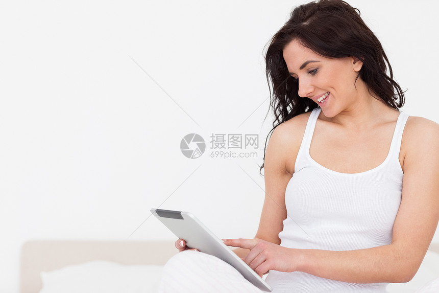 在使用触摸屏幕时坐着的棕发女人微笑图片