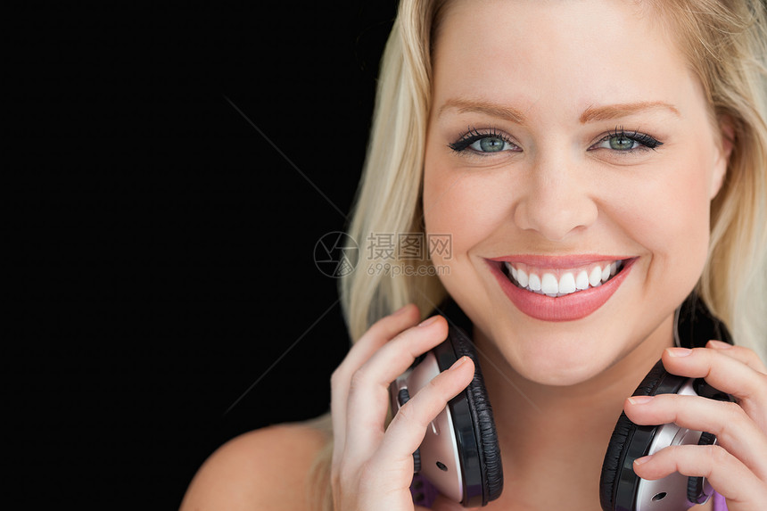 微笑的女人站立时拿着耳机图片
