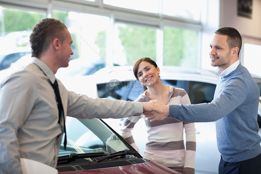 汽车经销商和一个笑着的人握手图片