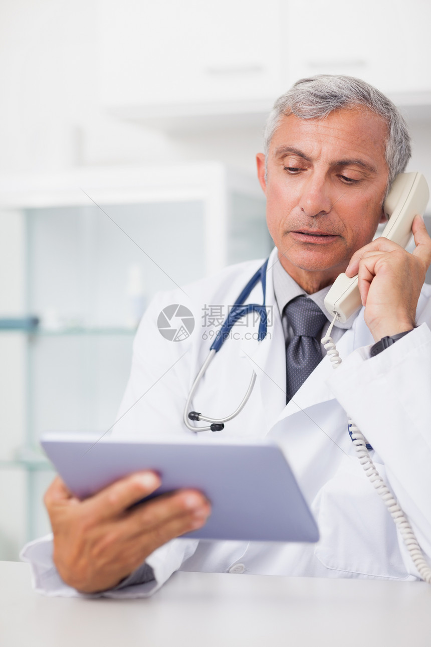 电话时持有平板电脑的医生图片