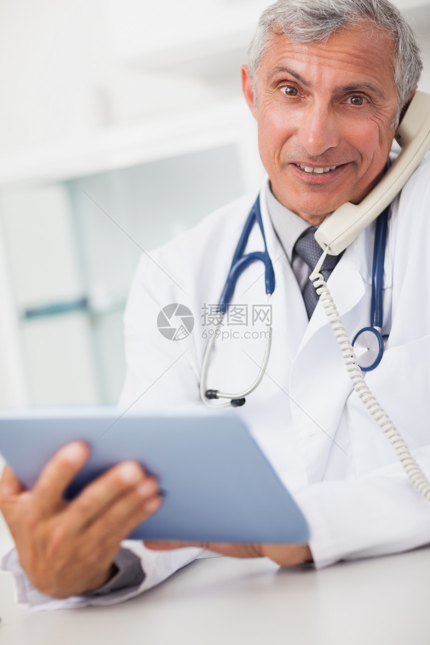 手持平板电脑和打电话的微笑医生图片
