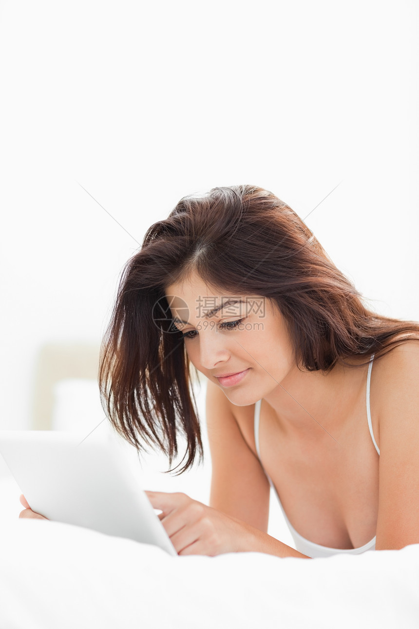 女人躺在床上时用平板电脑听力闲暇枕头划线房间外表爱好卧室双手快乐图片