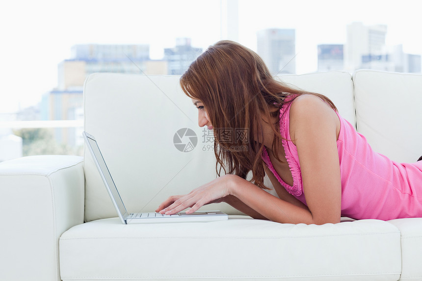 年轻妇女在使用键盘时看笔记本电脑图片