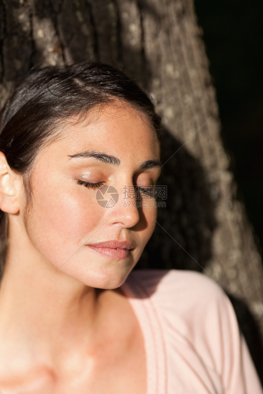 女人闭上眼睛 坐在树上像太阳一样的阳光图片