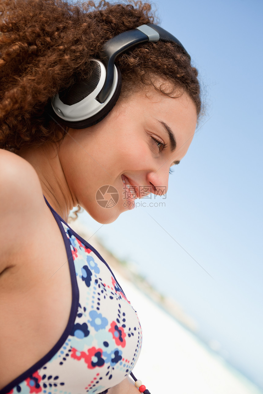 穿比基尼的年轻美女 在海滩上听音乐图片