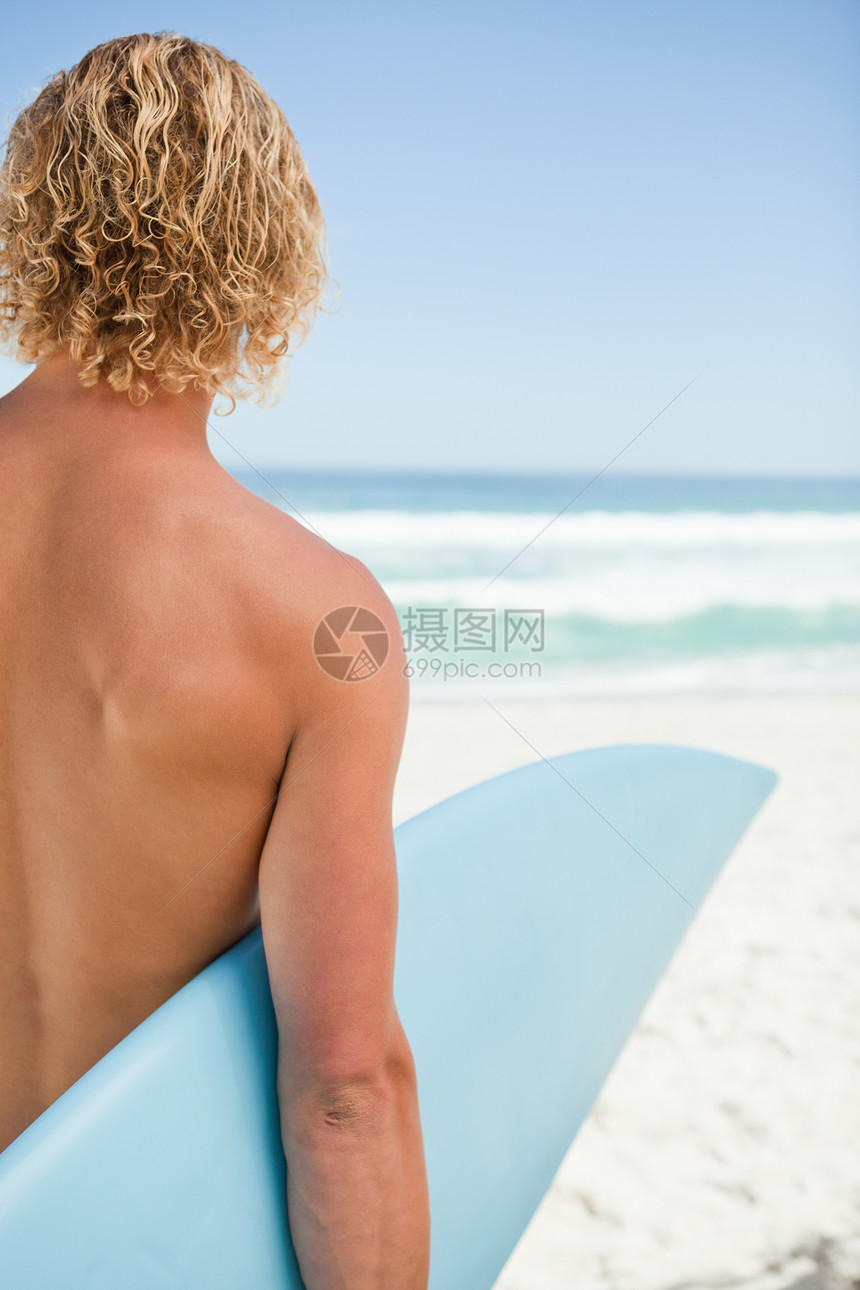 年轻金发金发男子拿着蓝冲浪板图片