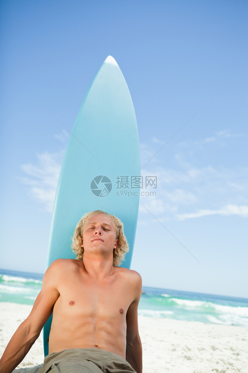 年轻放松的男人坐在沙滩上晒日光浴图片