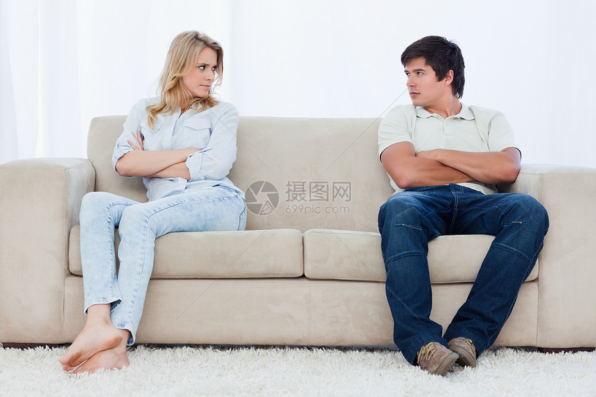 一对夫妇坐在沙发两端 双臂折叠长椅年轻人对方外表女性划线夫妻金发女郎斗争图片