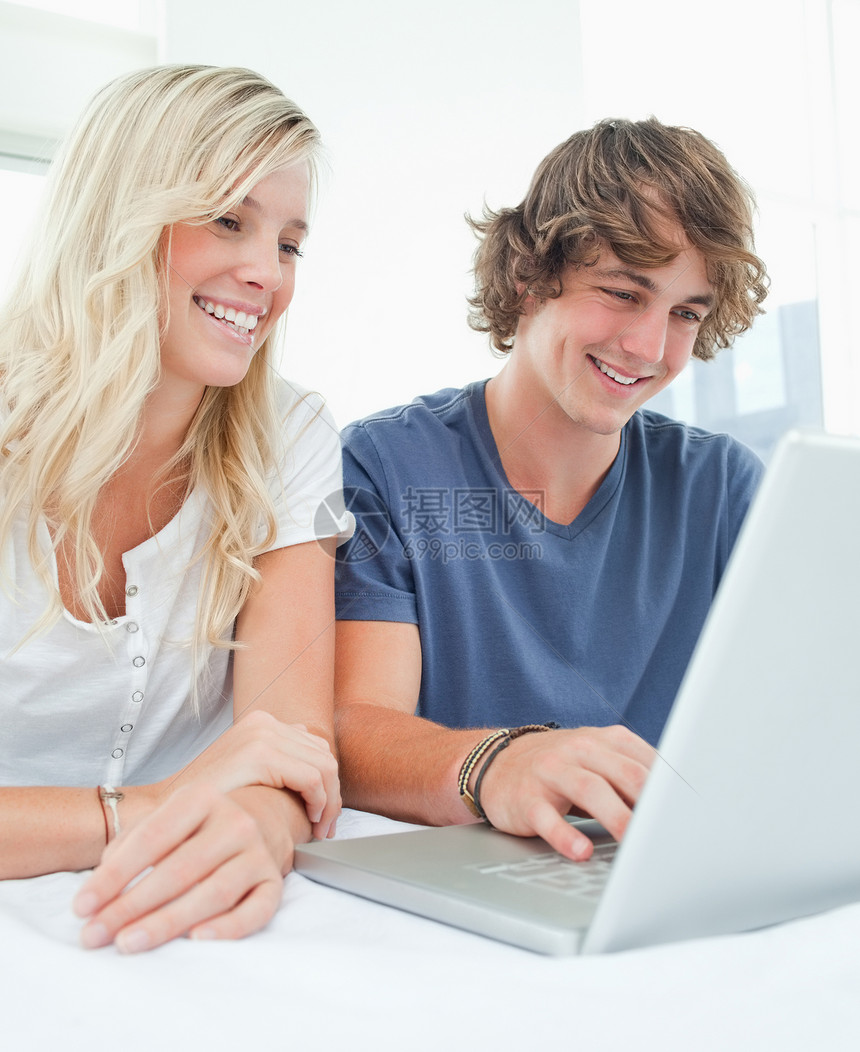 一对微笑的情侣在上网时坐在一起图片