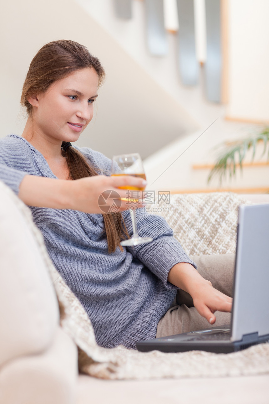 一个女人在使用时喝着一杯白葡萄酒的肖像图片